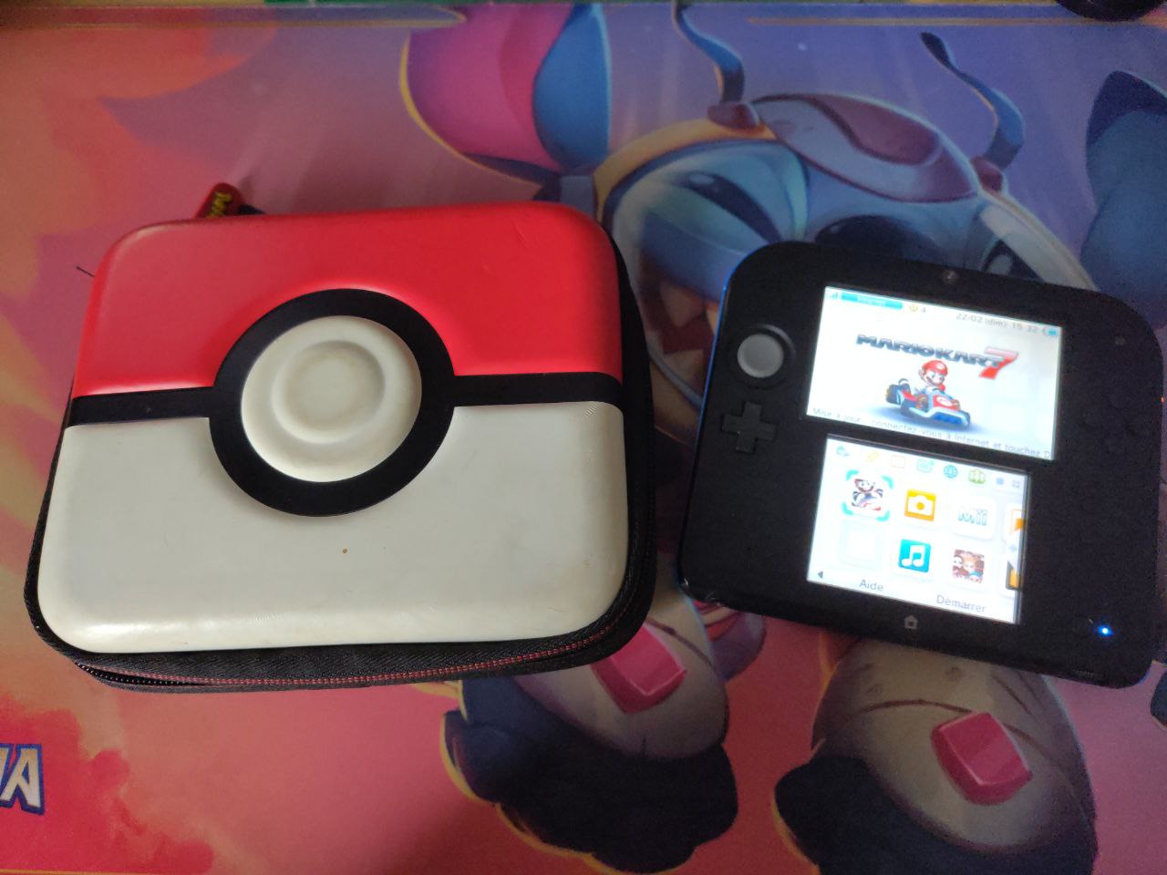 A black 2DS on the left, and its Pokémon-themed carrying case on the left