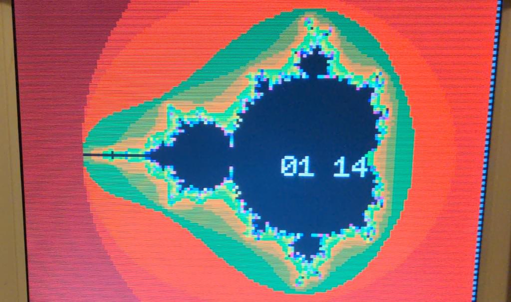 A monitor showing a very colorful but very pixelated representation of the Mandelbrot set. A chronometer lies in the center of the screen.