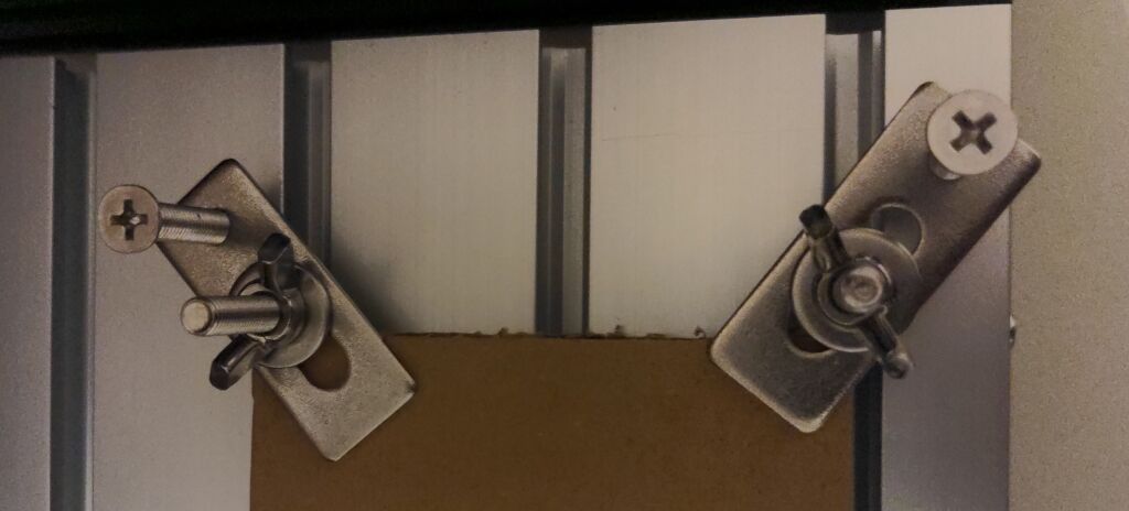 a close up of two clamps fastening the cardboard to the bed of the CNC routeur