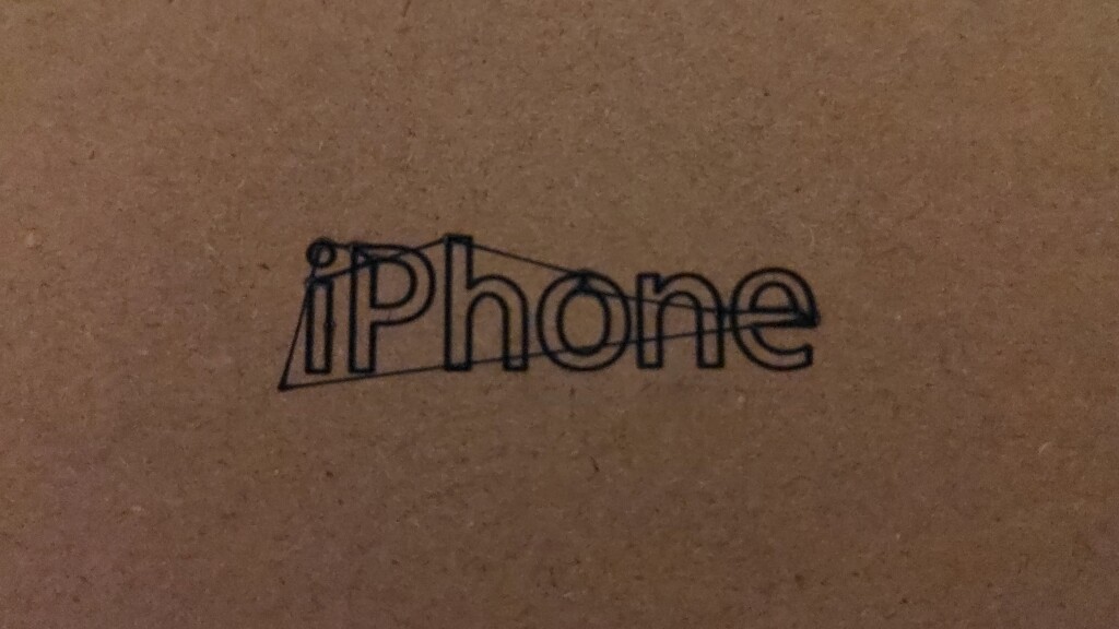 iPhone laser-engraved on a piece of cardboard, with extraneous lines connecting some letters together